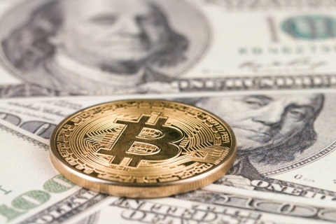 Bitcoin on top of US dollar bills.
