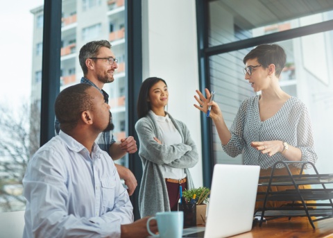 Four coworkers discussing how to conduct salary benchmarking
