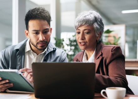 Two business people working with a tablet and laptop in an office