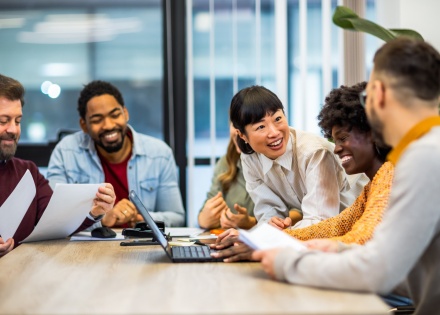 colleagues-standing-around-a-laptop