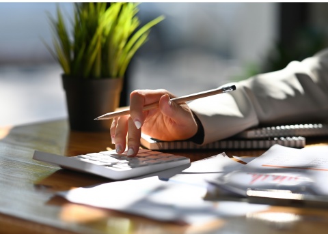 Person calculating budget on desk. 