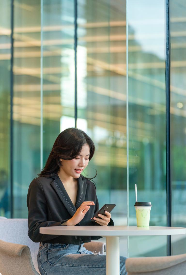 Employer using Pebl EOR on phone sitting at table with coffee