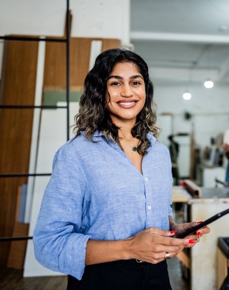 Female employer smiling at the camera while holding a tablet.