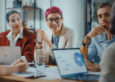 Business men and women sitting around an office table collaborating on a work project.
