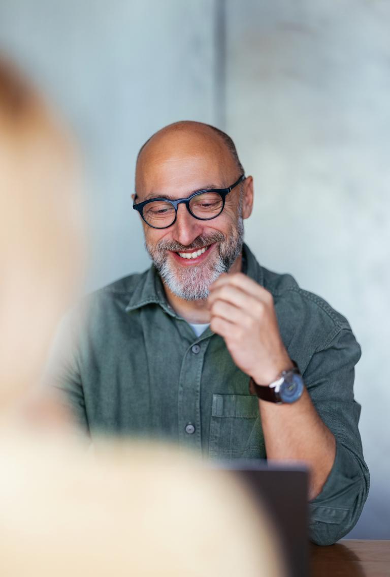 Male employer smiling while looking Pebl M&A services on computer.