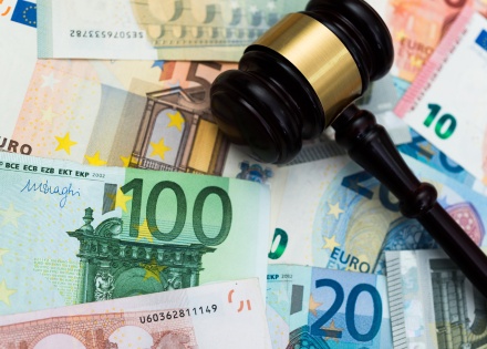 A gavel lying on top of various euro banknotes