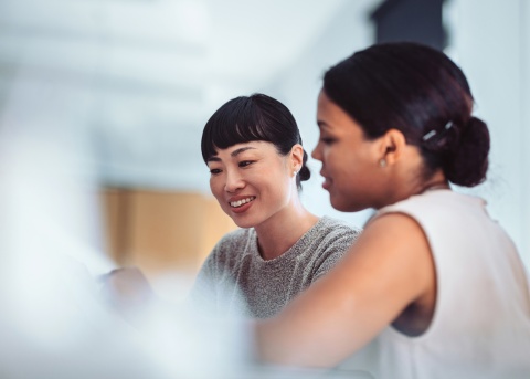Two female HR professionals discussing global hiring and recruitment strategies