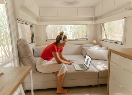 Woman sitting in her RV van with head phones, taking a video call