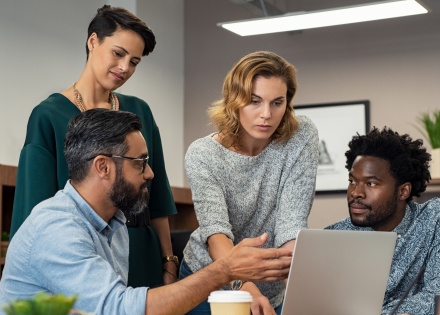 HR professionals huddling around a laptop discussing human capital risk