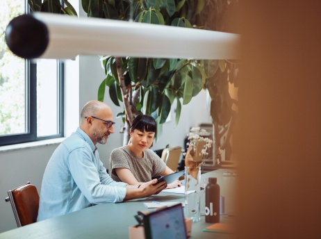 Side view of man and woman colleagues reviewing Pebl EOR services on tablet.