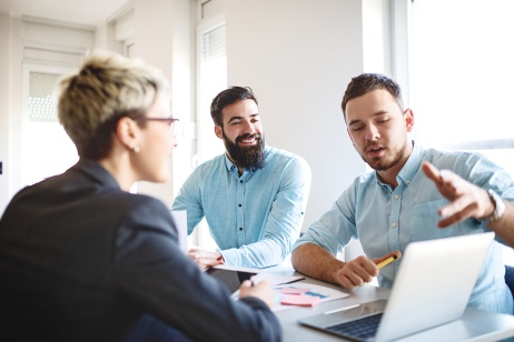 hree colleagues discussing Pebl M&A while looking at laptop.