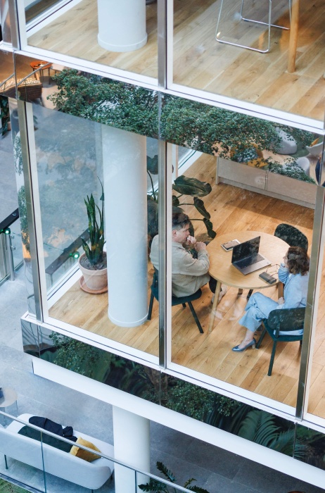Overhead view of colleagues meeting in a modern office building with glass walls.