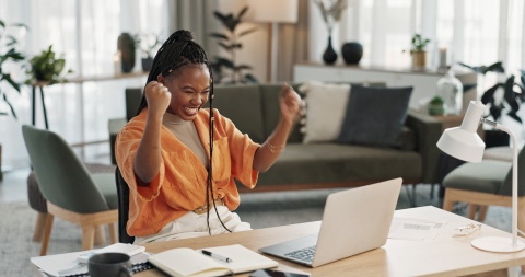 Woman cheering at her laptop while learning about types of cryptocurrencies