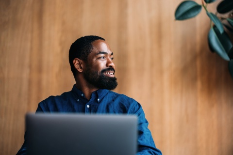 Professional man smiling and working on a laptop in a modern office in Sudan