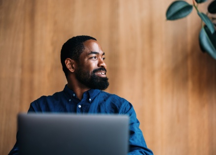 Professional man smiling and working on a laptop in a modern office in Sudan