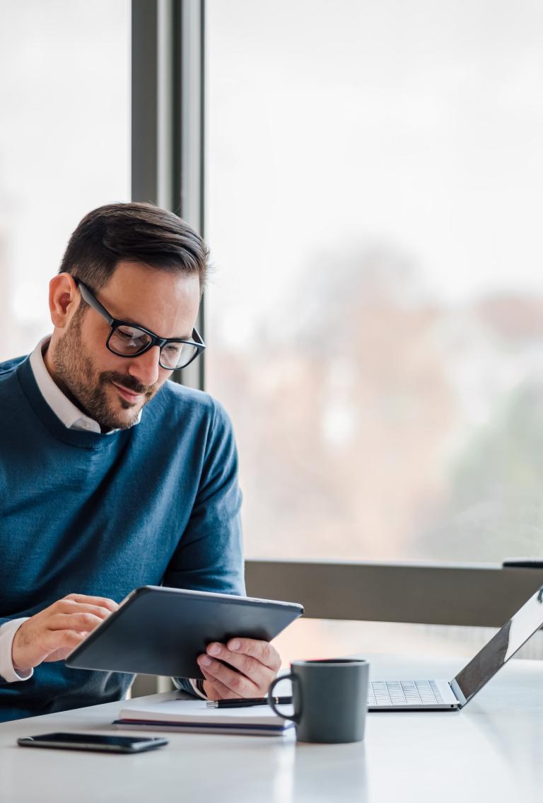 Male employer in office setting reviewing Pebl EOR for consulting firms on tablet.