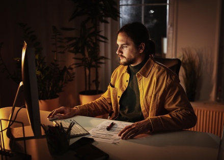A young professional working from his home office deep into the night.