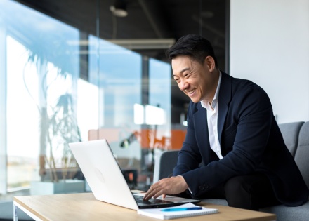 Smiling businessman working on a laptop in an office in South Korea