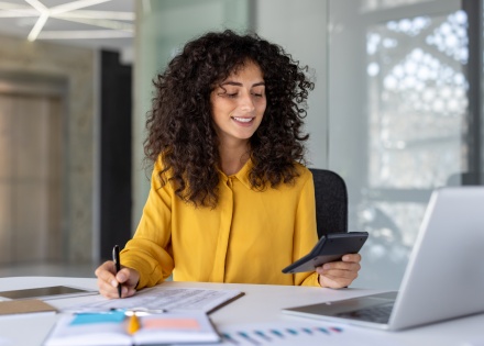Smiling businesswoman using a calculator to calculate payroll taxes in Mongolia