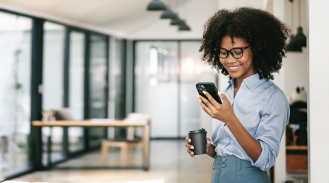 Smiling curly-haired businesswoman using smartphone in office in Congo