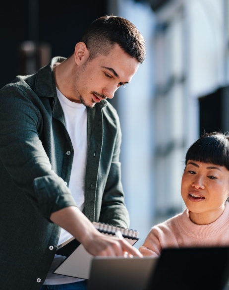 Two colleagues analyzing global expansion costs on computer.