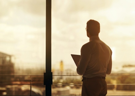 Business professional looking out window in dramatic lighting