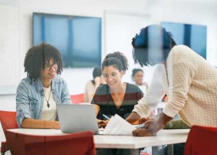 Three people collaborating around laptop.