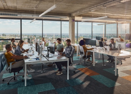 Co-workers at naturally lit office working at their desks