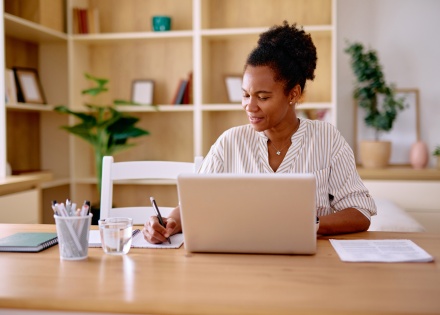 Woman taking notes while calculating payroll taxes in Malawi