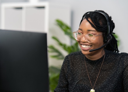 Woman wearing headset sitting at desk in front of computer screen