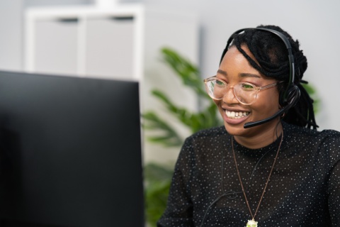 Woman wearing headset sitting at desk in front of computer screen