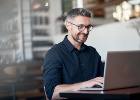 Male remote employee works from his laptop at restaurant. 
