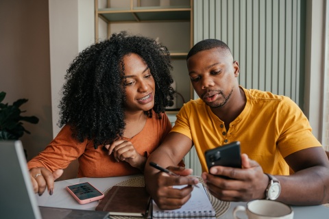 Young couple looking at phone discussing payroll taxes in Togo