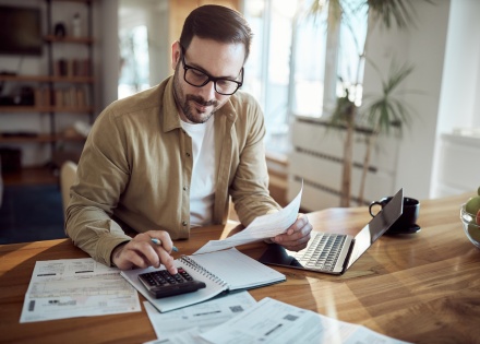 Young man using a calculator while working on payroll taxes in the Bahamas