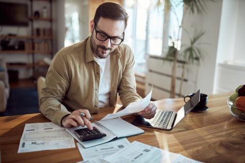Young man using a calculator while working on payroll taxes in the Bahamas