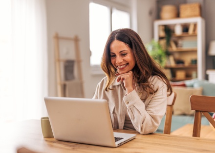 Young woman smiling and working from home on her laptop in Kuwait