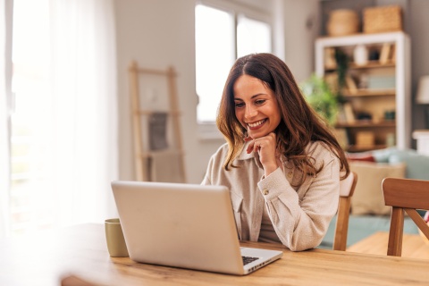 Young woman smiling and working from home on her laptop in Kuwait
