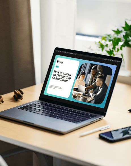 Laptop on desk with How to Attract and Retain Top Global Talent guide opened up.