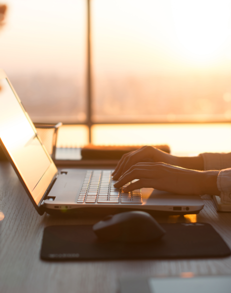 Laptop and mouse on a table with sunset in the background