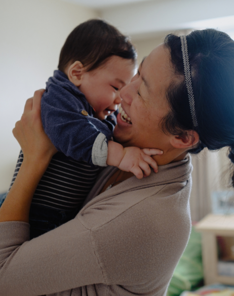Asian woman holding baby up to her chest